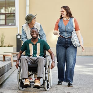 Three friends wheeling friend in wheelchair